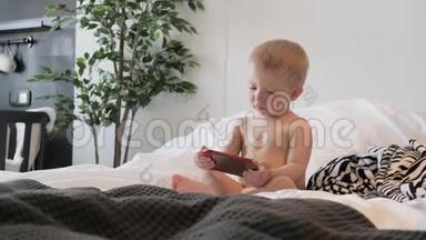 小男孩在家里的床上看智能手机上的卡通，生活方式。